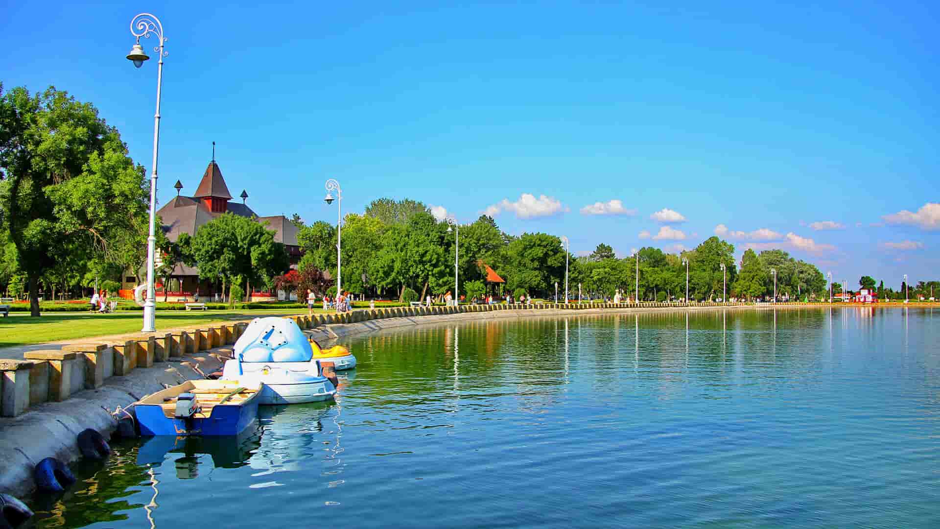 Palićko jezero sa šetalištem, čamcima i plavim nebom.