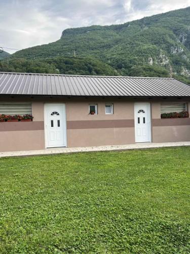 Uređeno zeleno dvorište sa otvorenim bazenom i ležaljkama u objektu Apartmani Savić u Perućcu
